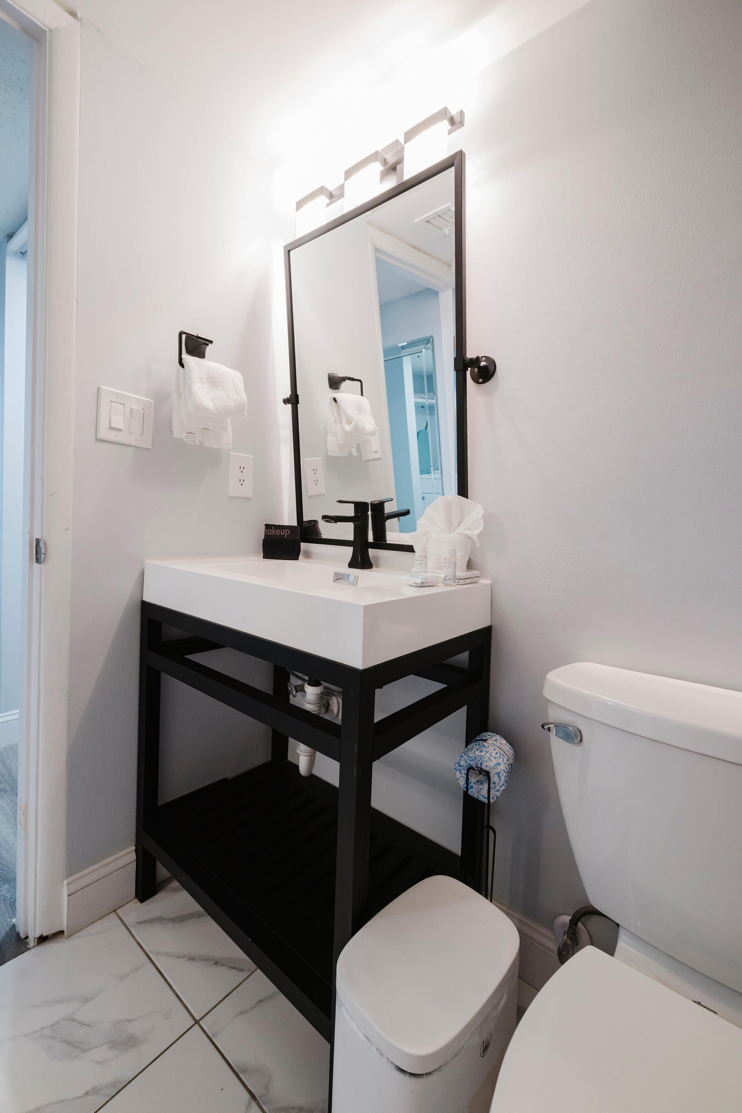 A bathroom with a white sink, black vanity, and a white toilet.
