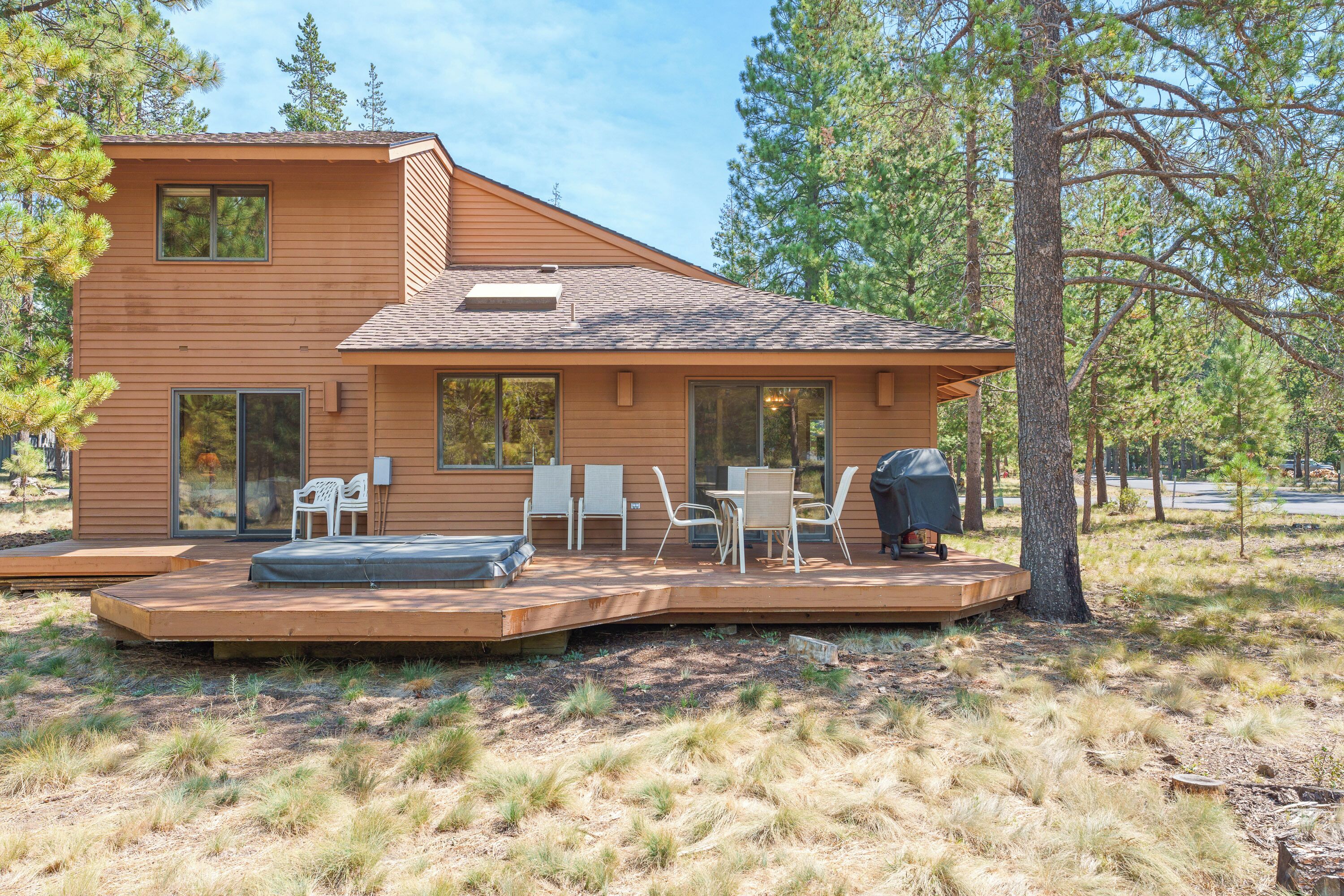A modern house with a deck, outdoor seating, and a hot tub.
