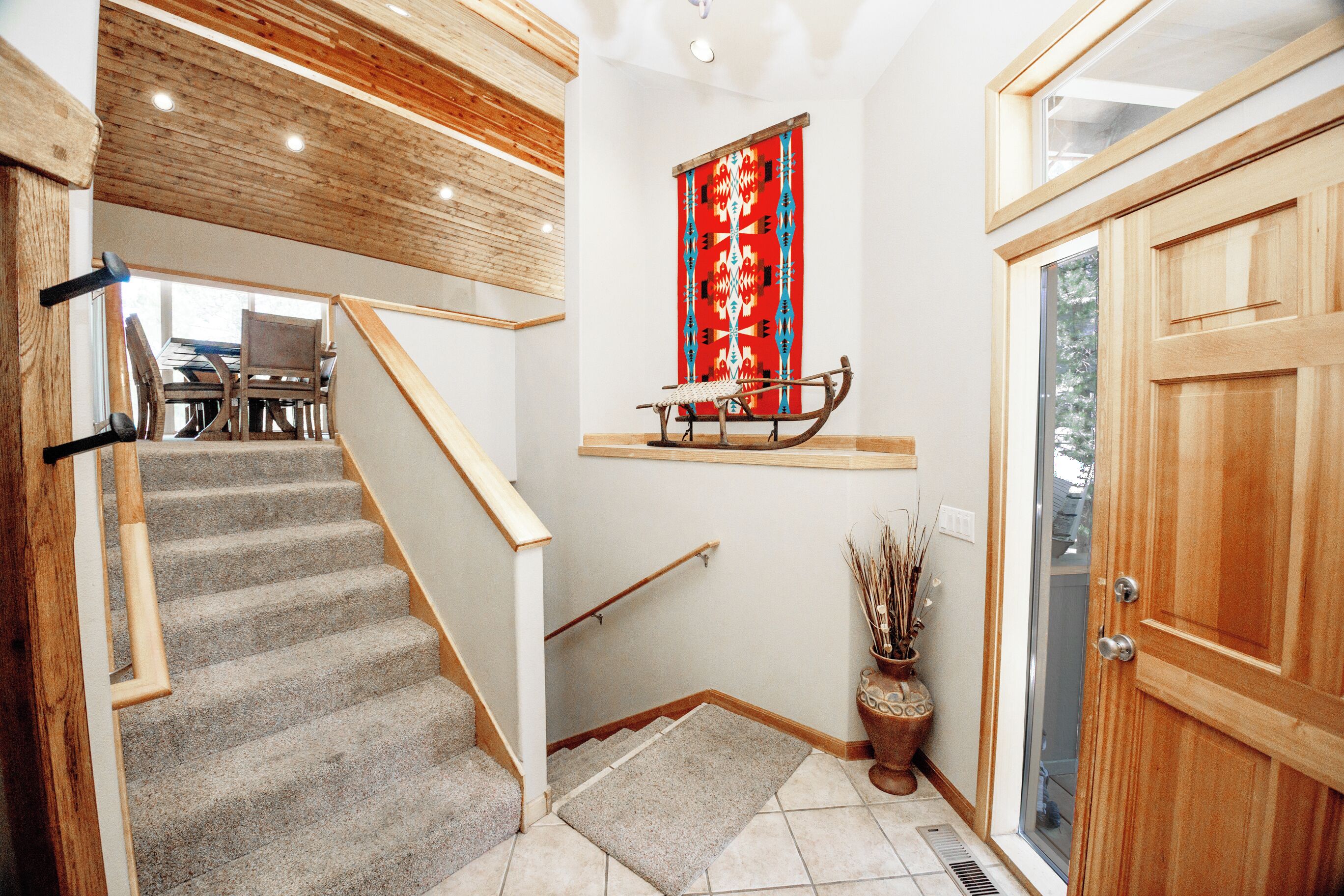 A staircase with a wooden handrail, carpeted steps, and a wooden door on the right.