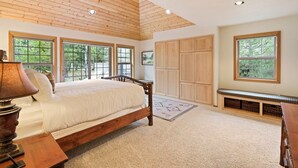 A bedroom with a wooden bed, large windows, a bench, and built-in storage. - Tokatee 14 - Beautiful & Spacious, SHARC, Ping Pong, A/C, Hot Tub (Sunriver)