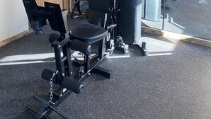 Een fitnessruimte met een halterbank, een squatrek en een spiegel.
