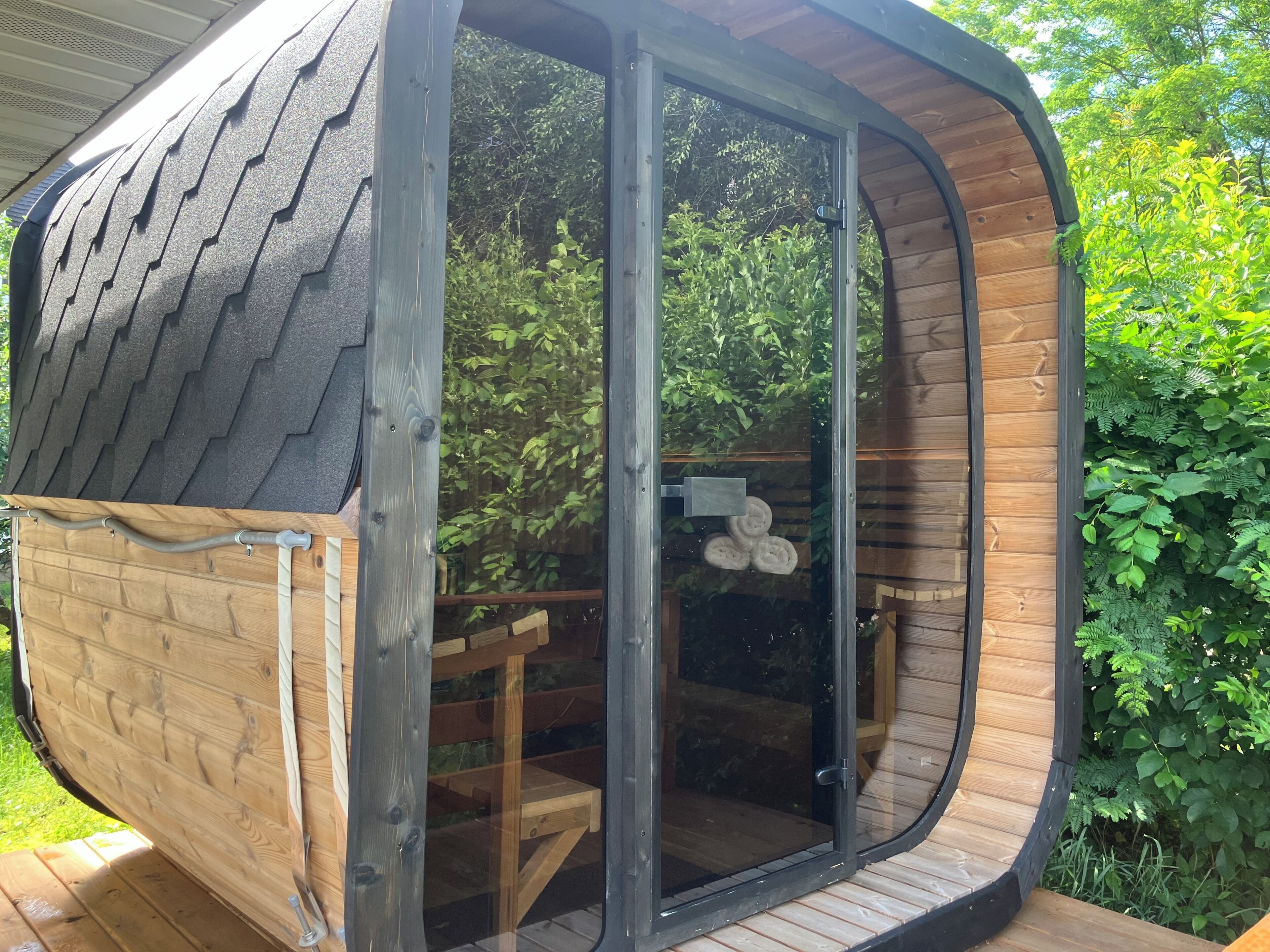 Una cabaña de madera con techo curvo y puerta corredera de vidrio.