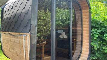Una cabaña de madera con techo curvo y puerta corredera de vidrio.