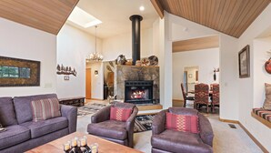 A cozy living room with a stone fireplace, leather sofas, and a wooden coffee table. - Summit View 5 - Updated Single Level, SHARC, A/C, Hot Tub (Sunriver)