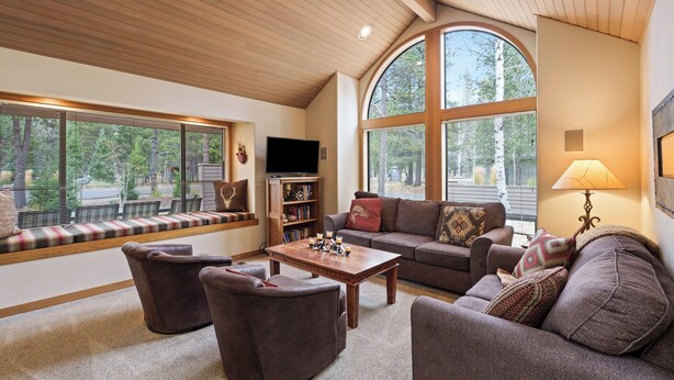 A cozy living room with a large window, a television, a fireplace, and comfortable seating. - Summit View 5 - Updated Single Level, SHARC, A/C, Hot Tub (Sunriver)