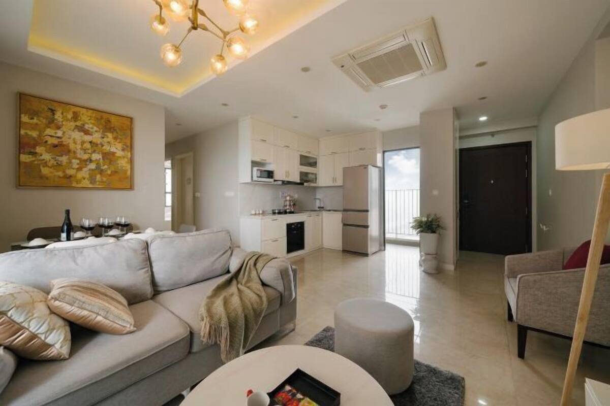 A modern living room with a sofa, ottoman, and a dining table.