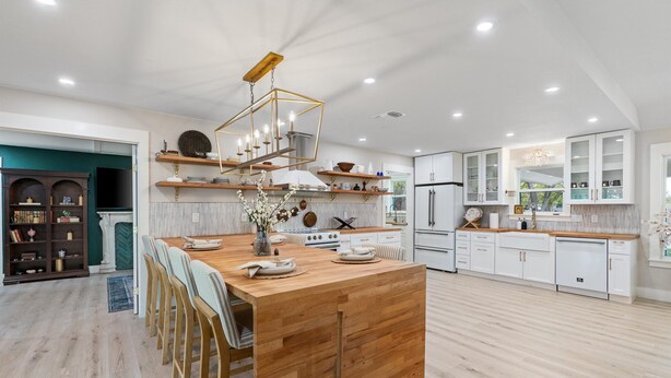 Una cocina moderna con una isla de madera, armarios blancos y una estufa empotrada.