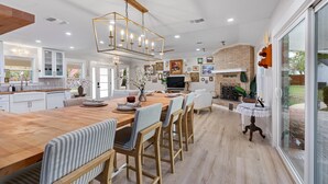 Una cocina amplia con una isla grande, electrodomésticos modernos y un comedor con sillas a rayas.