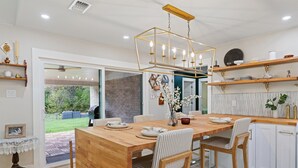 Una cocina moderna con una mesa de comedor de madera, armarios blancos y una lámpara colgante.