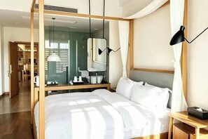 A modern hotel room with a large bed, a bedside table, a mirror, and a lamp. - Mount Emei Baiyuting Yunjian Tangquan B&B (Emeishan)