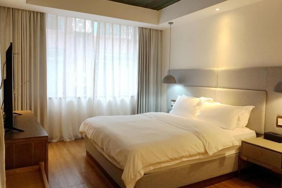 A hotel room with a large bed, a bedside table, a lamp, and a TV.