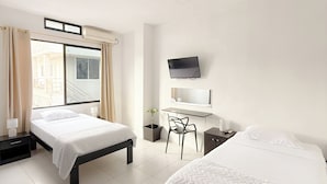 Une chambre d’hôtel avec deux lits, un bureau, une chaise, une télévision et une fenêtre avec des rideaux.