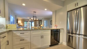 A modern kitchen with white cabinetry, a stainless steel refrigerator, and a dishwasher.