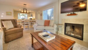 A living room with a fireplace, a sofa, a coffee table, and a television mounted on the wall.