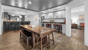 Uma cozinha moderna com mesa de madeira, banquetas e forno embutido.