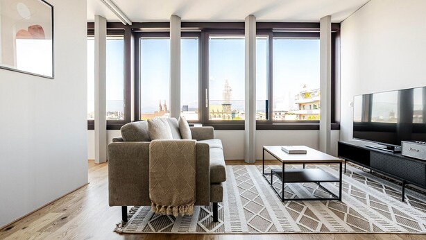 A modern living room with a sofa, TV, and large windows offering city views. - Blueground | Basel-Vorstaedte, view, nr Kunstmuseum (Basel)