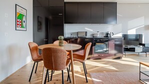 Una cocina moderna con armarios oscuros, una mesa redonda y sillas naranjas.