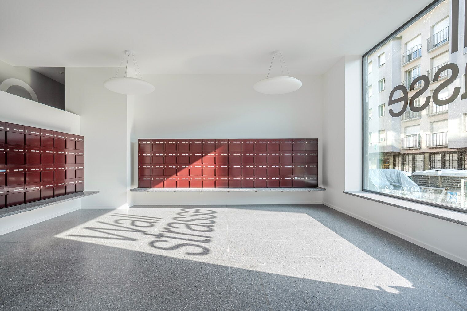 Un intérieur moderne avec des casiers, une grande fenêtre et un sol agrémenté de flèches directionnelles.