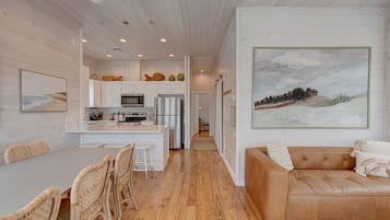 A modern kitchen with white cabinetry, a central island, and a dining area with wicker chairs.