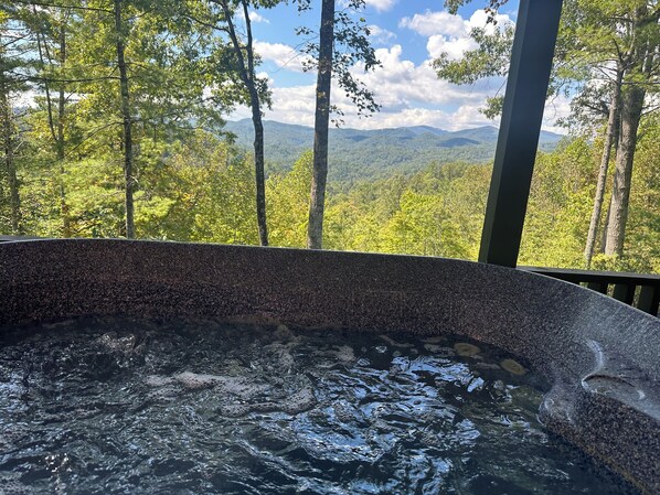 A hot tub with a view of a forest and mountains.