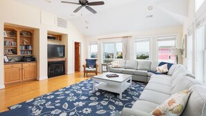 Ein großzügiges Wohnzimmer mit Kamin, einer breiten Couch, einem Couchtisch und einem Fernseher.
