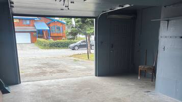 Eine offene Garage mit Betonboden, einem Holzstuhl und einer blauen Wand.