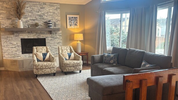 A living room with a stone fireplace, two armchairs, a sofa, and a large window with curtains. - Relaxing-Retreat, Anchorage Getaway, Cozy & Newly Remodeled (Anchorage)
