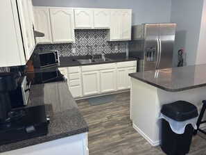A modern kitchen with white cabinets, a stainless steel refrigerator, a microwave, and a sink. - Cozy Guest Suite on working farm (Honea Path)
