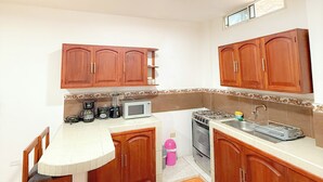 A compact kitchen with wooden cabinets, a microwave, a coffee maker, and a gas stove.