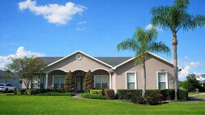 A single-story house with a front porch, a garage, and a well-maintained lawn. - 4BR family home w/ pool & lanai (Lakeland)