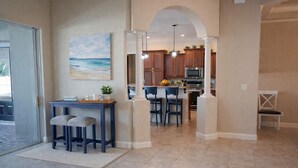 A kitchen with a central island, wooden cabinets, and a hanging light fixture. - 4BR family home w/ pool & lanai (Lakeland)