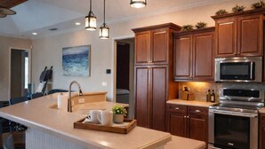 A modern kitchen with a central island, stainless steel appliances, and wooden cabinetry. - 4BR family home w/ pool & lanai (Lakeland)