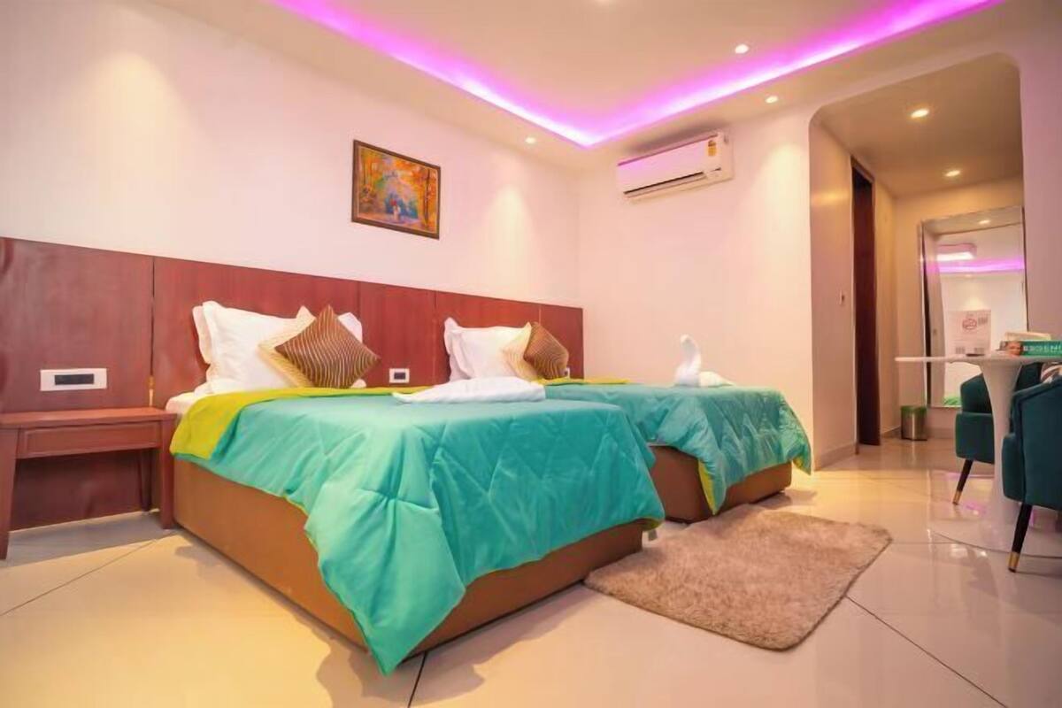 A hotel room with two beds, a desk, and a chair.