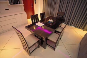Un comedor con una mesa de madera oscura, seis sillas y un armario blanco.