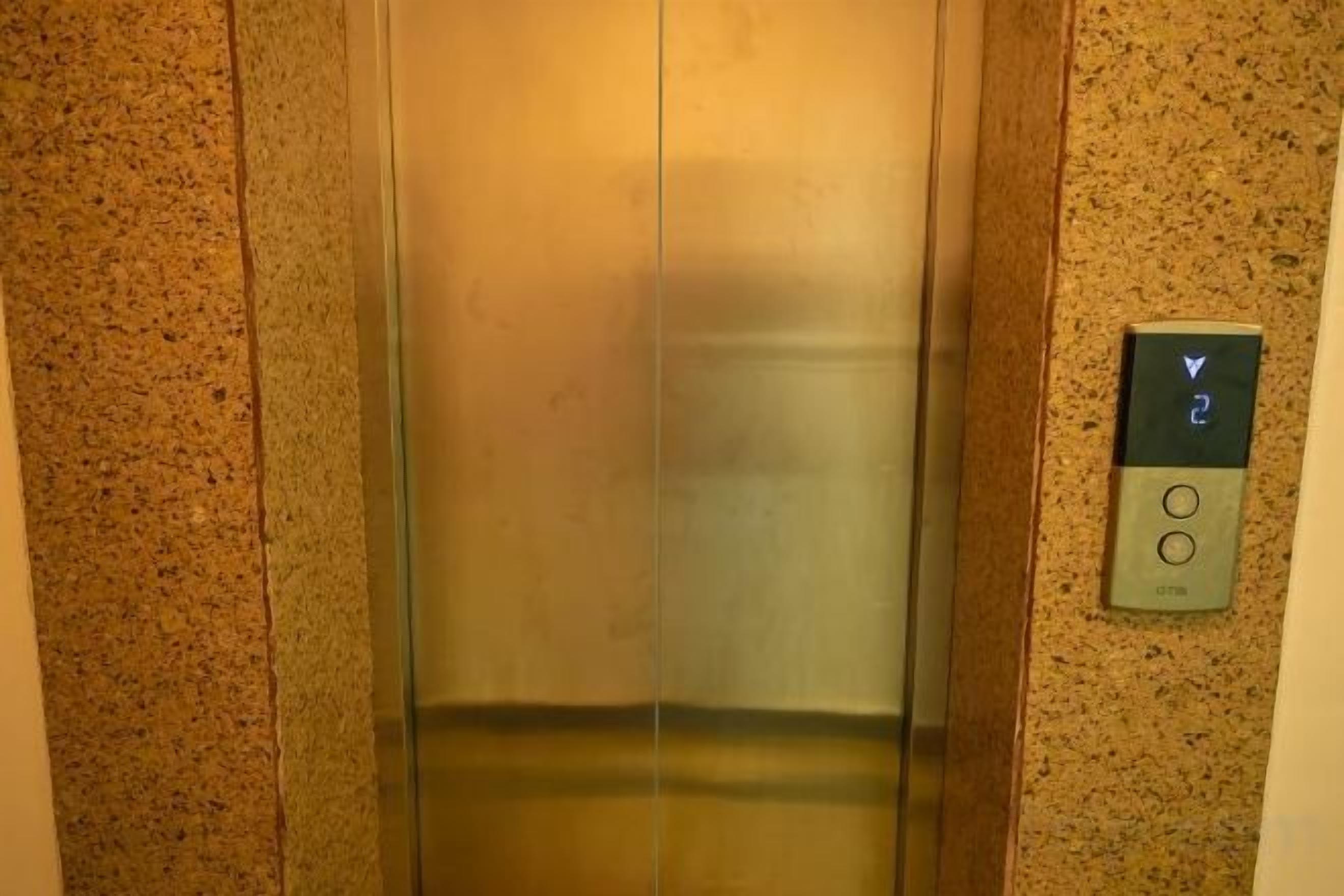 Um elevador com painel de controle exibindo uma seta para baixo e o número 2.