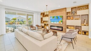 A modern living room with a large sofa, a flat-screen TV, and a fireplace. - “Spacious 10BR Villa w/ Pool, Theater & Themed Kids’ Rooms – Near Disney” (Kissimmee)
