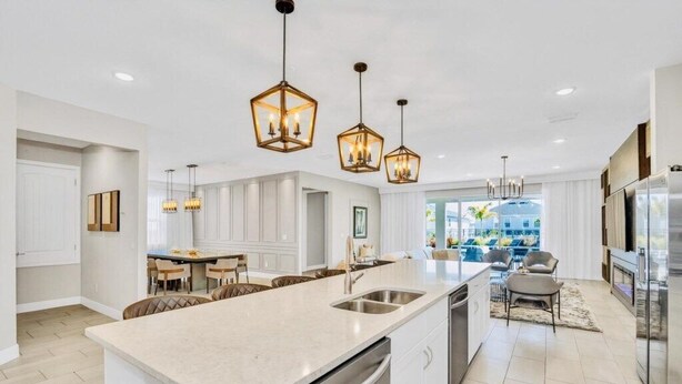 A modern kitchen with a central island, stainless steel appliances, pendant lighting, and a view to the outdoors. - “Spacious 10BR Villa w/ Pool, Theater & Themed Kids’ Rooms – Near Disney” (Kissimmee)