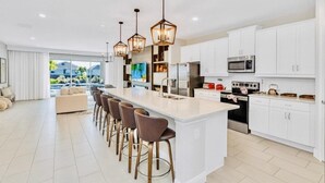 A modern kitchen with a central island, white cabinetry, and pendant lighting. - “Spacious 10BR Villa w/ Pool, Theater & Themed Kids’ Rooms – Near Disney” (Kissimmee)