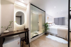 Una habitación de hotel moderna con una cama grande, un escritorio con ordenador, un espejo y una planta en maceta.