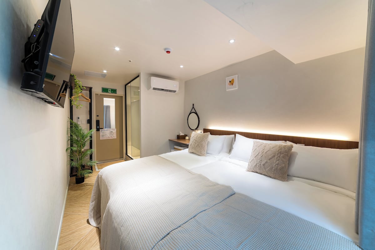 Een hotelkamer met een bed, nachtkastje en een aan de muur bevestigde televisie.