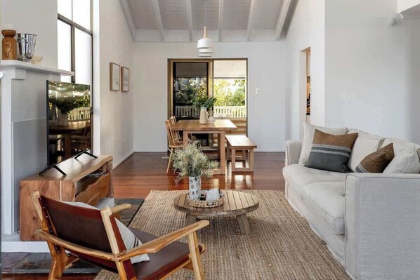 A spacious living area with a sofa, a wooden coffee table, and a dining table with chairs.