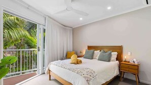 Une chambre à coucher avec un lit, une table de chevet et un balcon agrémenté de plantes.