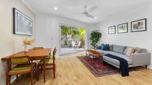 Un salon comprenant une table à manger, des chaises, un canapé, un ventilateur de plafond et des tableaux encadrés accrochés au mur.