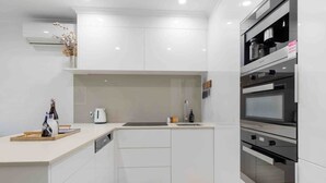 Une cuisine moderne avec des meubles blancs, un four encastré et un four à micro-ondes.