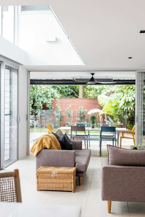 A modern living room with a sofa, armchairs, and a wicker basket.