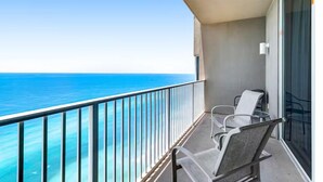 A balcony with a clear view of the ocean, two chairs, and a glass door. - Tidewater 3006 (Panama City Beach)