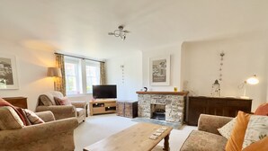 Una sala de estar acogedora con chimenea, sofás cómodos, una mesa de centro de madera y un televisor.