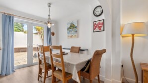 Un coin repas comprenant une table, des chaises, une lampe et une horloge au mur.