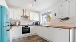 Une cuisine moderne avec des meubles blancs, un réfrigérateur bleu, un four à micro-ondes et un four encastré.
