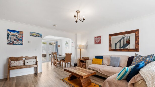 Un salon avec un banc en bois, un canapé, une table basse et, au fond, un coin repas.